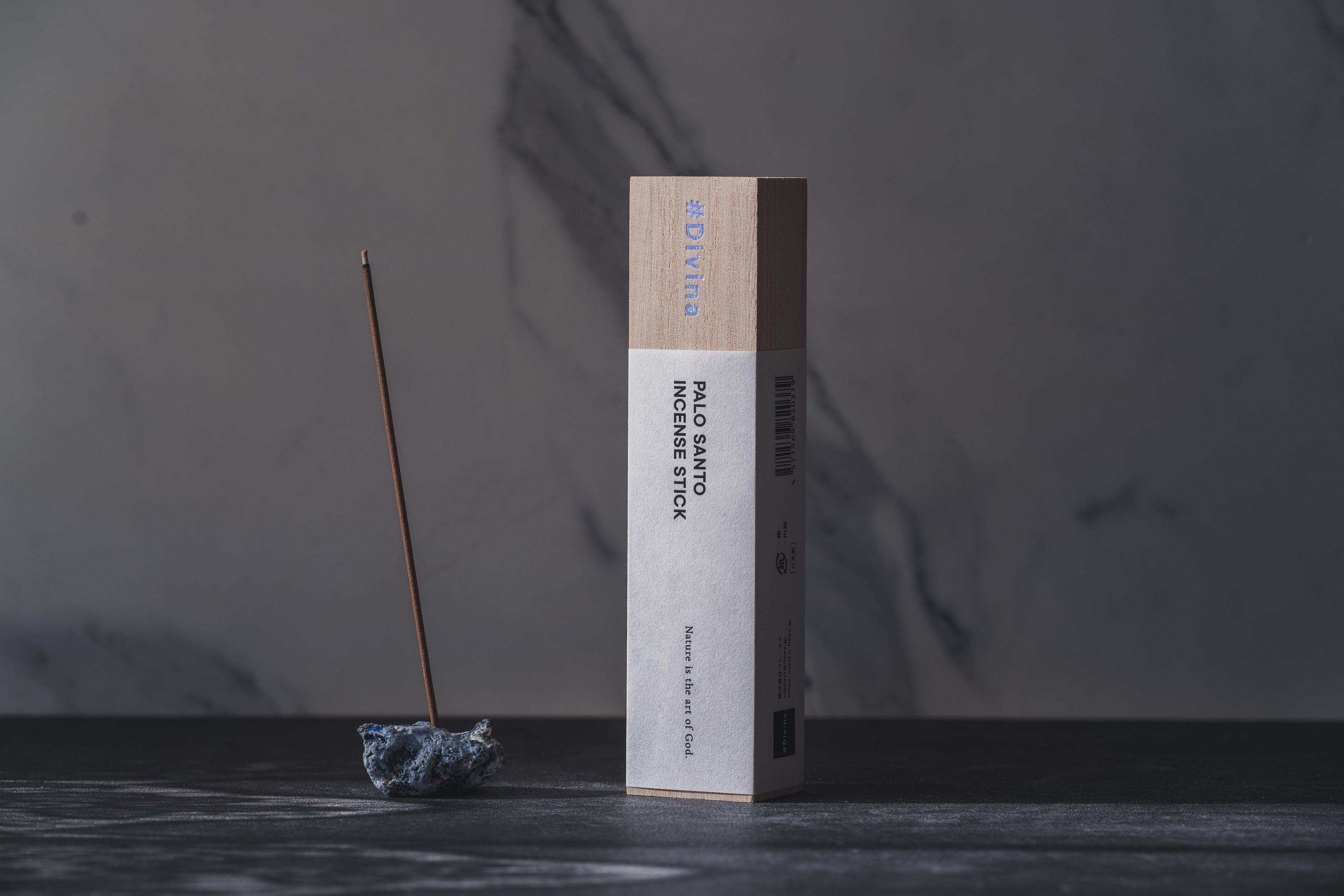 PALO SANTO INCENSE STICKのパッケージを、青い石の香立てに1本挿した状態と並べて撮影した様子